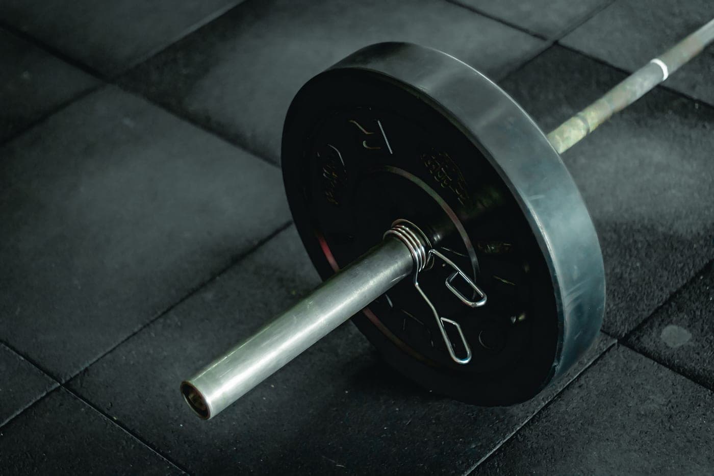 A knurled steel barbell loaded on a rack