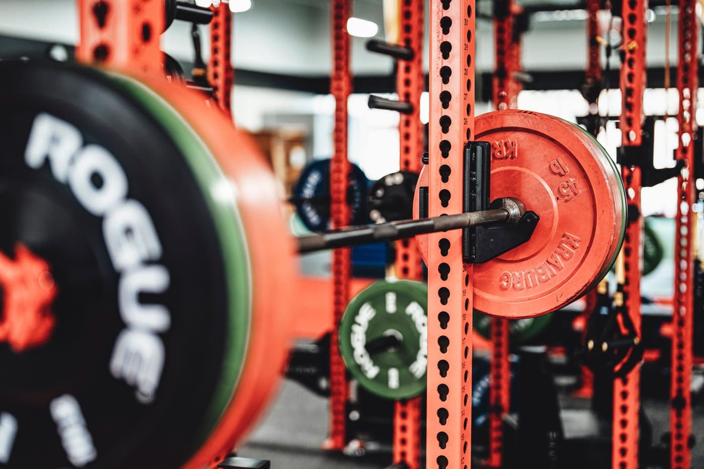A home garage gym with a loaded barbell and a steel power rack